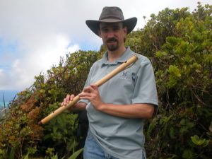 Photo of the composer holding a shinobue in the Ko'olau Mountains